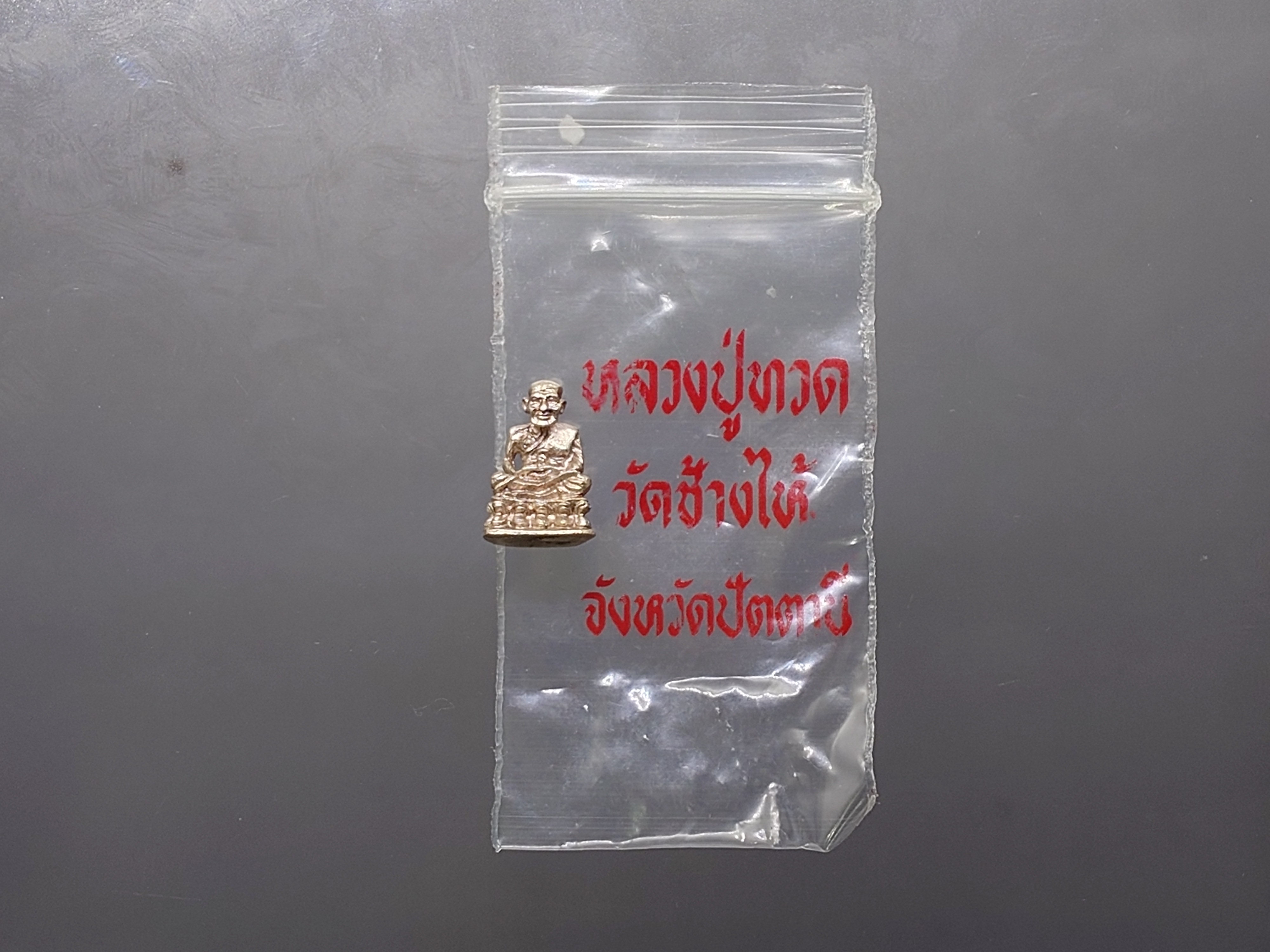 หลวงปู่ทวด หัวไม้ขีด พิมพ์แขนทะลุ เนื้อเงิน (ลอยองค์ จิ๋ว) อาจารย์นอง ปลุกเสก วัดช้างให้ ปี2535 พร้อมซองเดิม