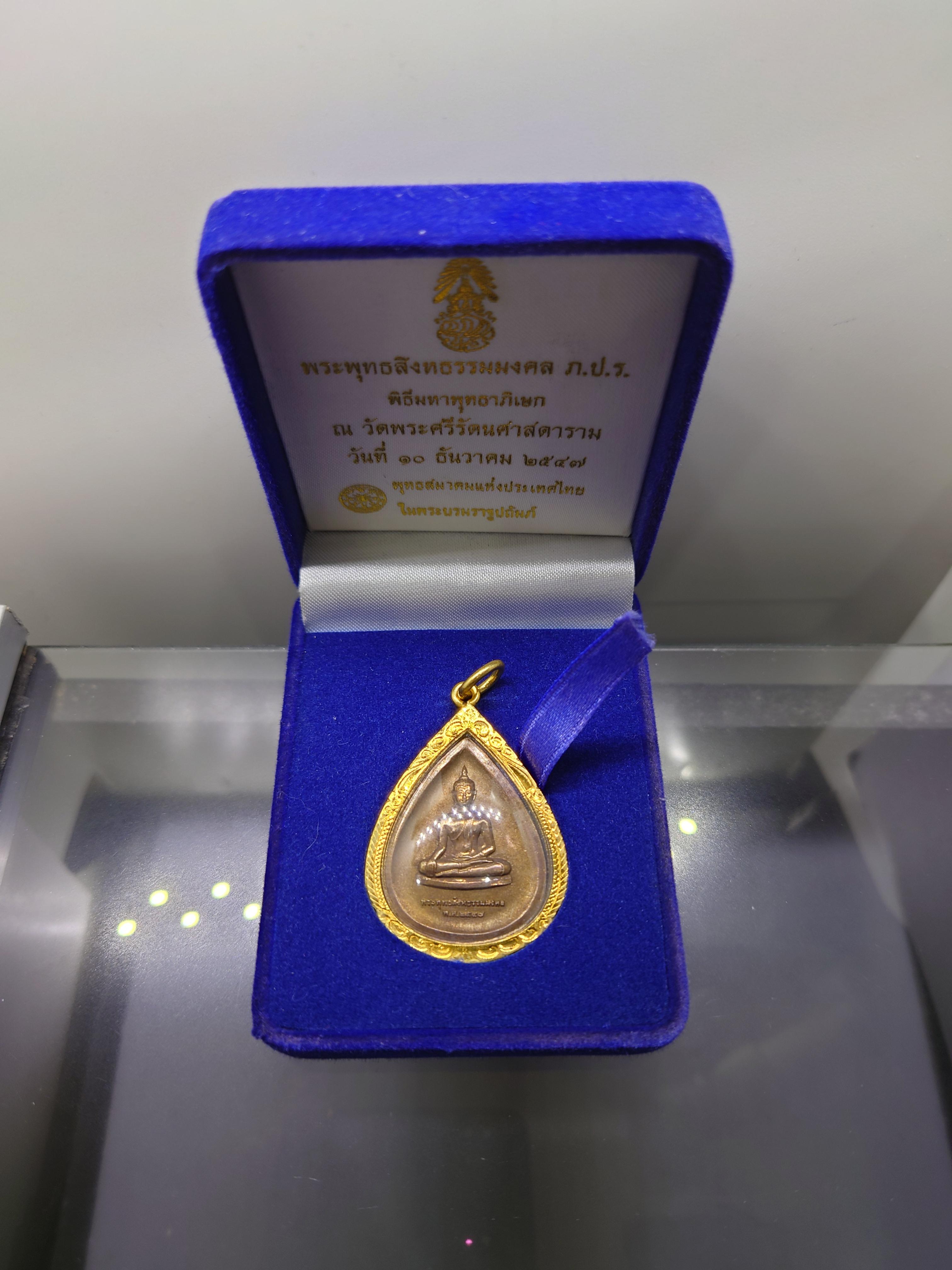 พระพุทธสิงหธรรมมงคล หลังพระปรมาภิไธย ภ.ป.ร. เนื้อนวะ พุทธสมาคมแห่งประเทศไทย ในพระบรมราชูปถัมภ์ พ.ศ.2547 เลี่ยมกรอบทองนพเก้า พร้อมตลับเดิม